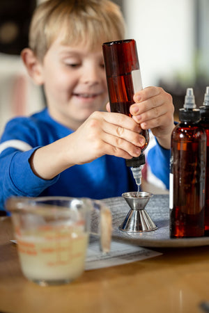 fragrance oil being poured into jigger by young boy